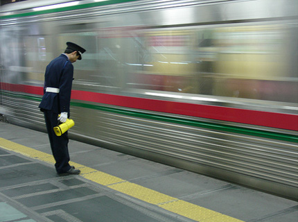 Một nhân viên nhà ga cúi mình chào hành khách trên tàu điện